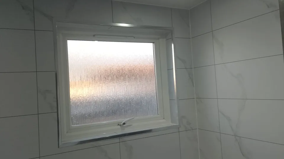 Frosted bathroom window and marble-effect wall finish