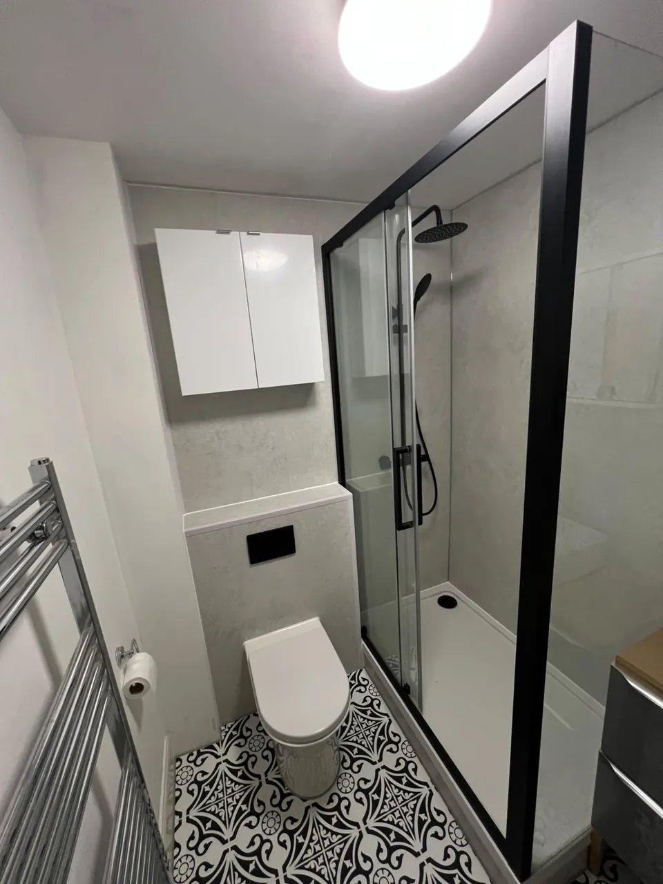 Black-framed shower with patterned flooring and white fittings